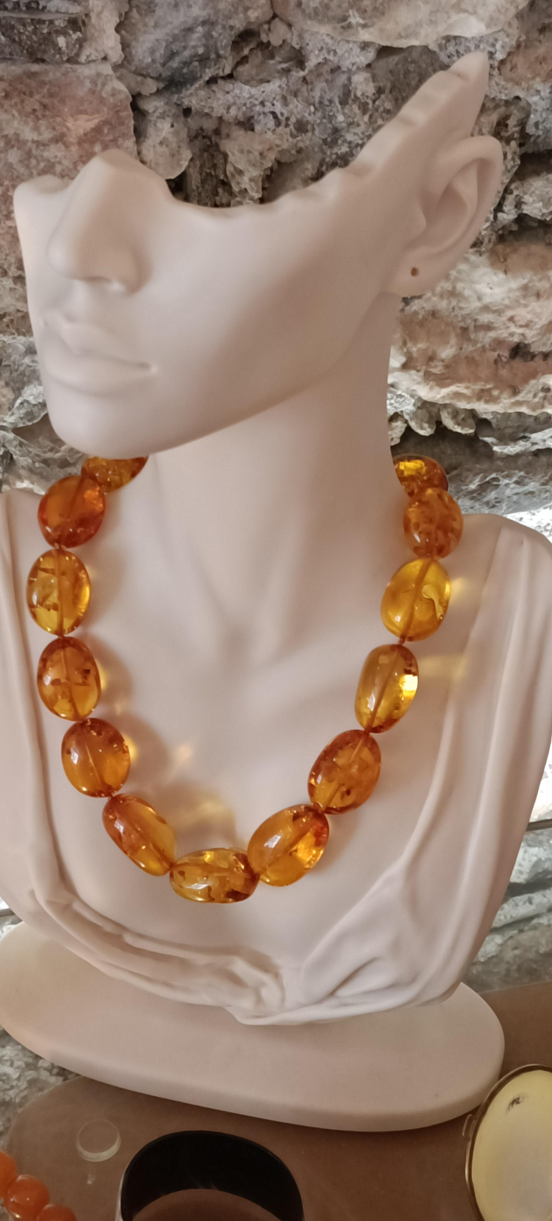 Bernstein-Kette auf Schmuckbüste vor Steinwand
